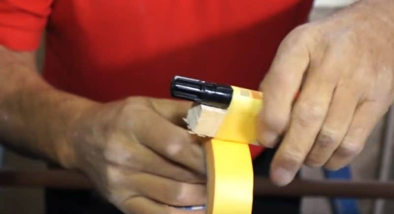 Der Edding muss mit Hilfe des Klebebands an den Holzblock befestigt werden Der Edding muss mit Hilfe des Klebebands an den Holzblock befestigt werden